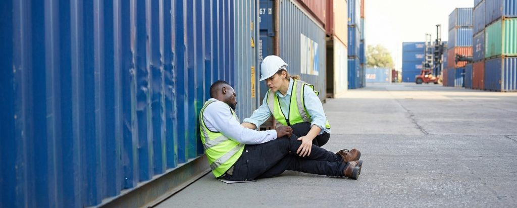 worker helping another fallen worker at shipping yard