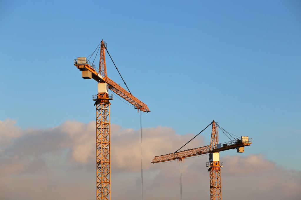 Construction,Cranes,On,Blue,Sky,And,White,Clouds,Background.,Housing